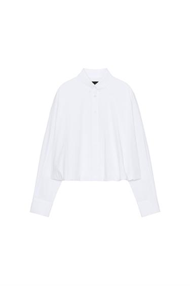 Front view of a white ripped shirt with a lapel collar, long sleeves and a puffed hem. Front button fastening.