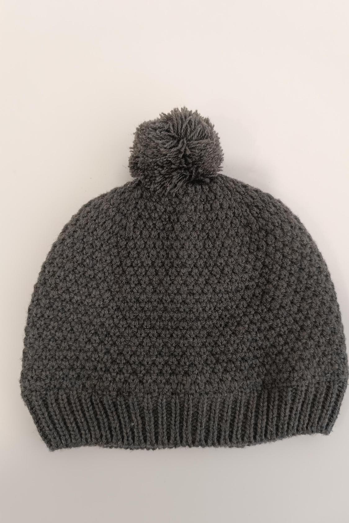 Front view of grey bobble hat with pom-pom and chunky knit.