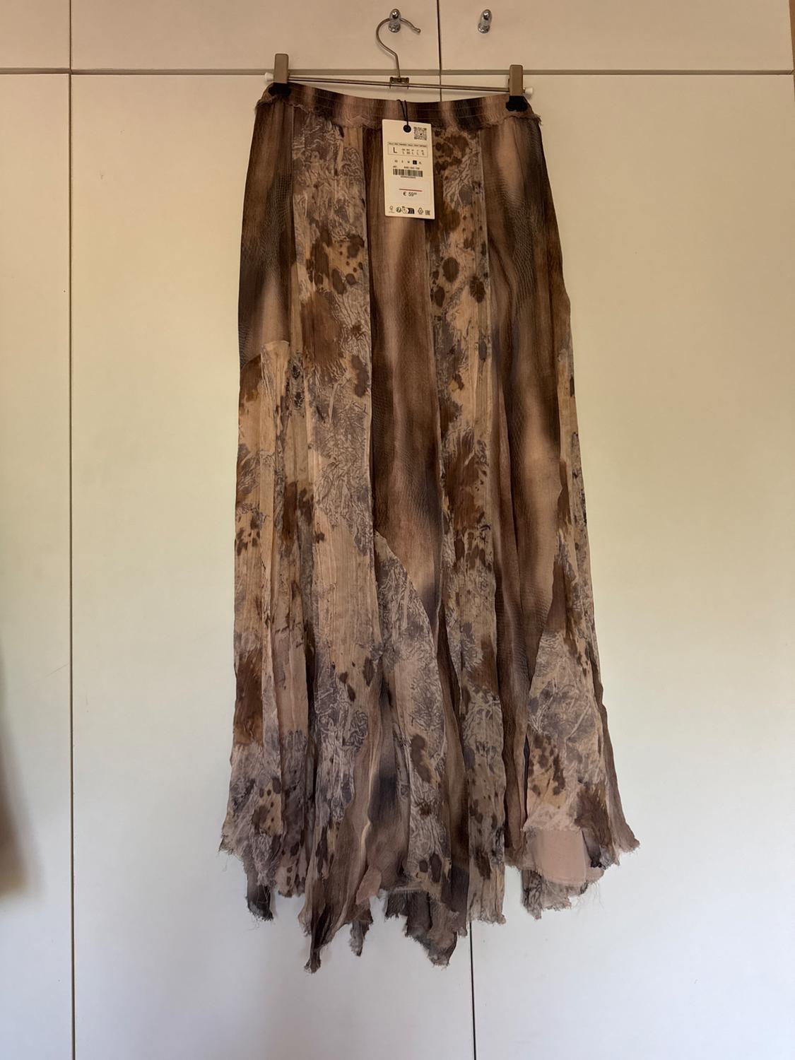 Long skirt with brown and beige print, hanging on a hanger. Visible label with text at the top centre.