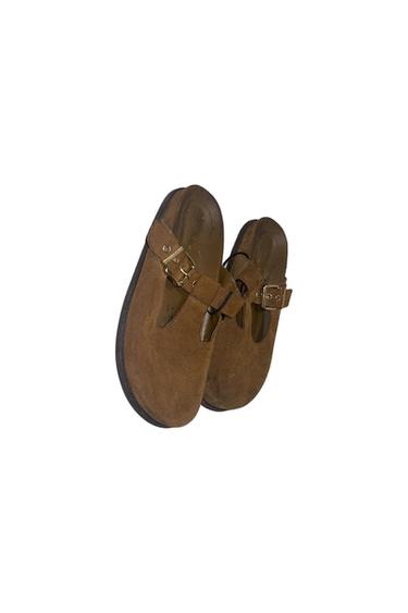 Pair of brown suede loafers with a strap and a metal buckle, shown at an angle on a white background.