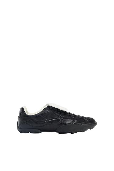 Black athletic shoe with textured panels and a contrasting white tongue, on a white background.
