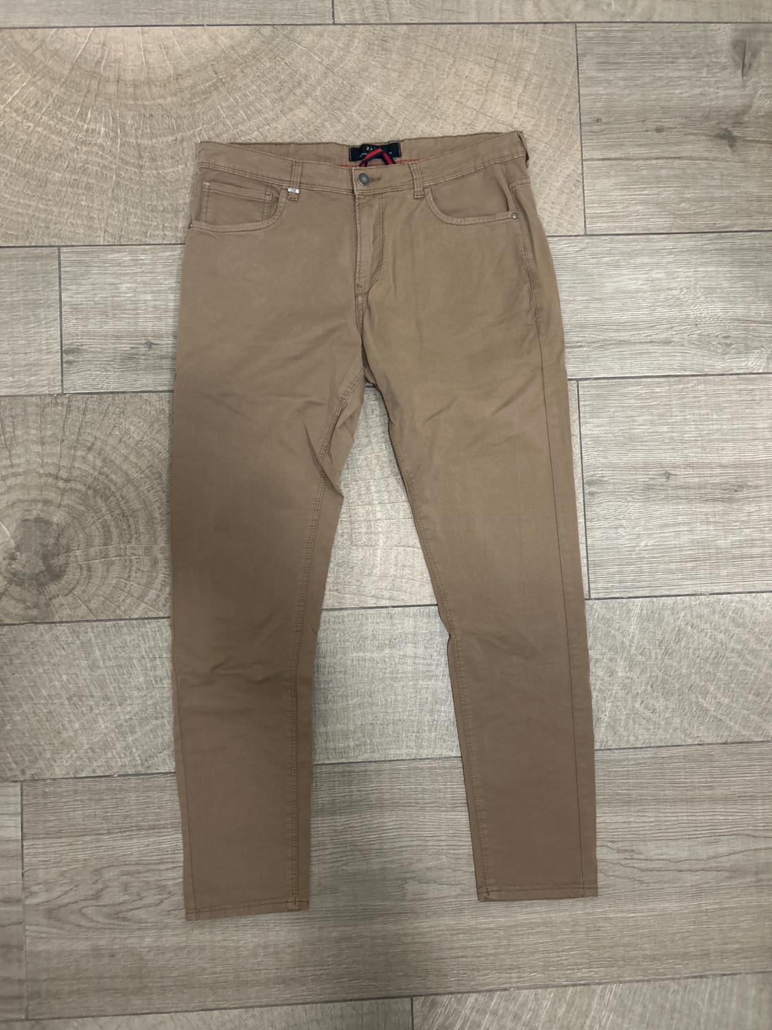 Brown straight-cut trousers on a light wooden floor with a visible ring pattern.