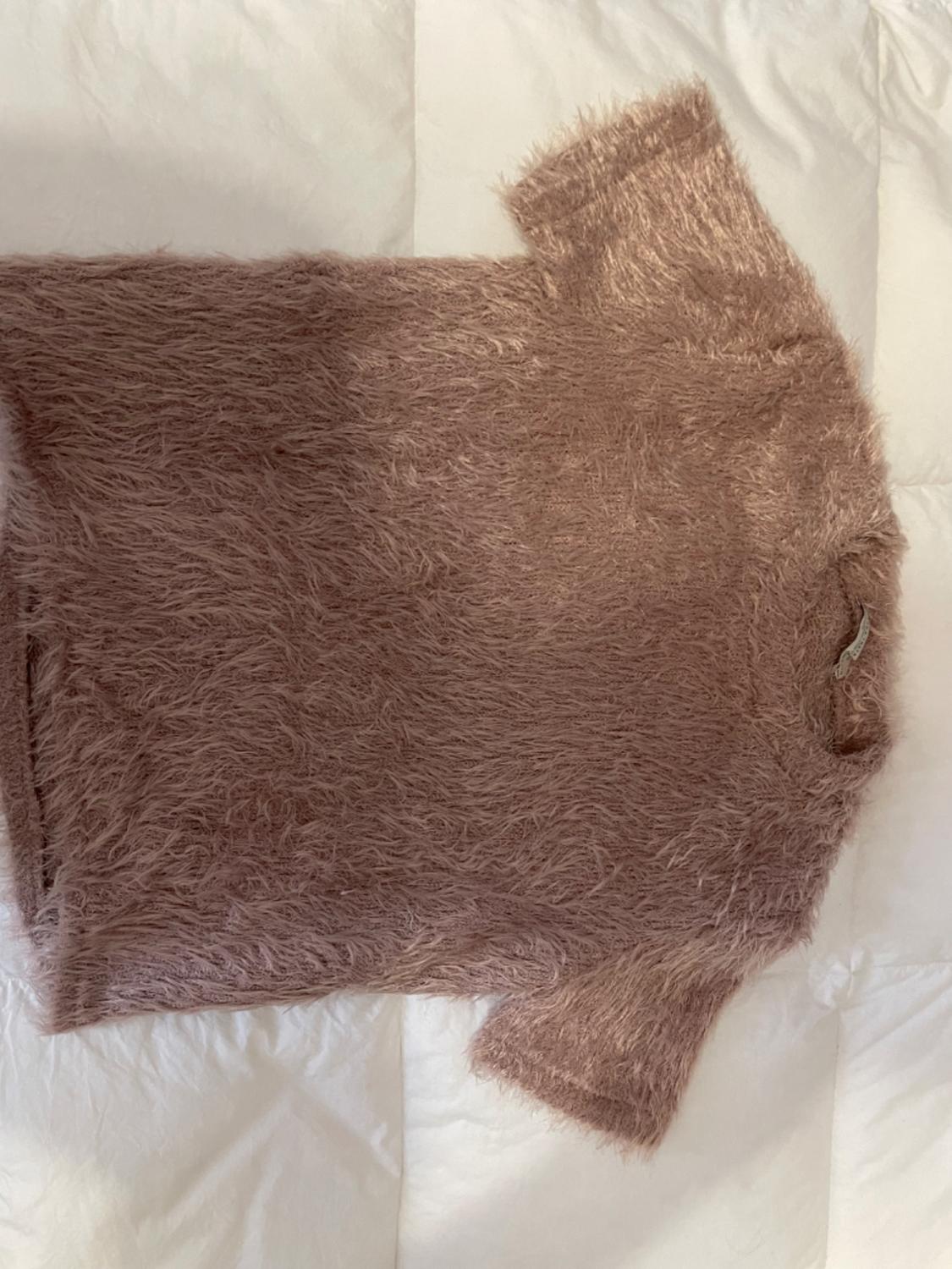 Light pink fluffy textured short-sleeved t-shirt, placed on a padded white surface.
