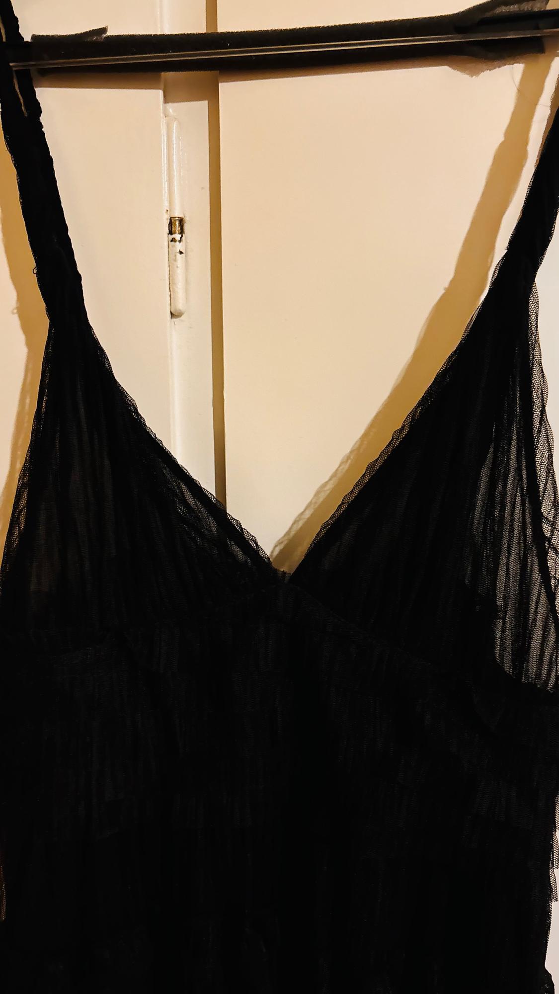 Black, spaghetti-strap dress hanging on a hanger over a white door. Light, translucent fabric.