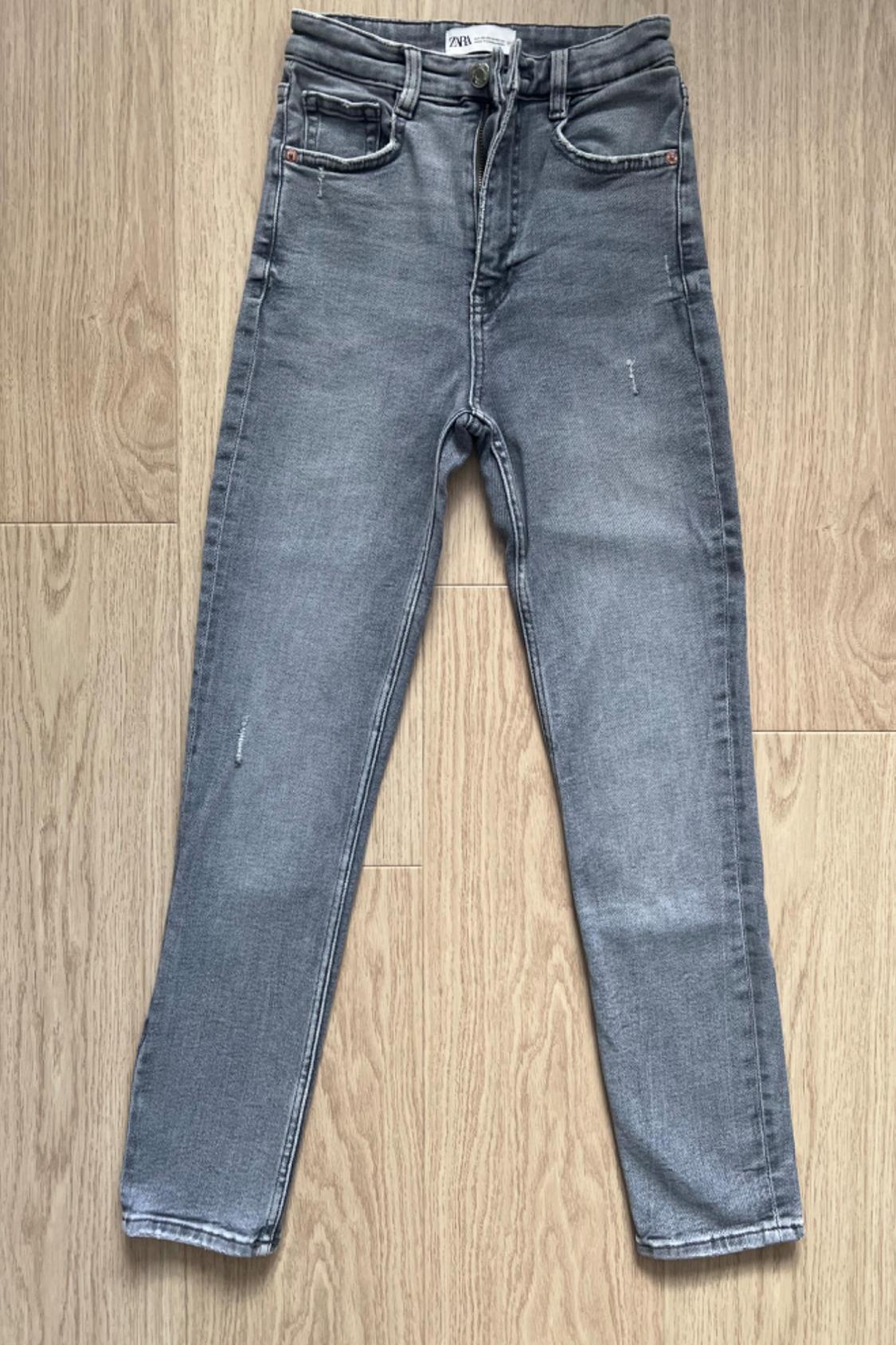 Front view of grey jeans with front pockets and light wear.