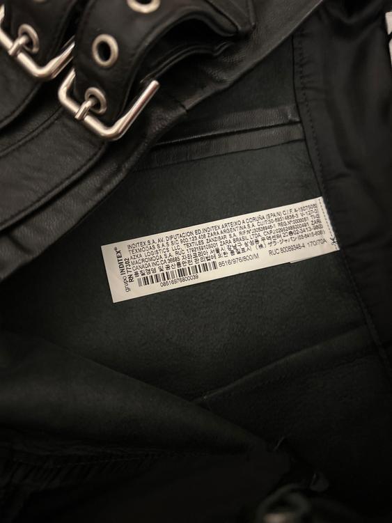 Clothing label on the inside of a black garment with metallic details. Visible text: "INDITEX S.A. AV. DIPUTACION ED. INDITEX ARTEIXO A CORUÑA (SPAIN) C.I.F. A-15075062".