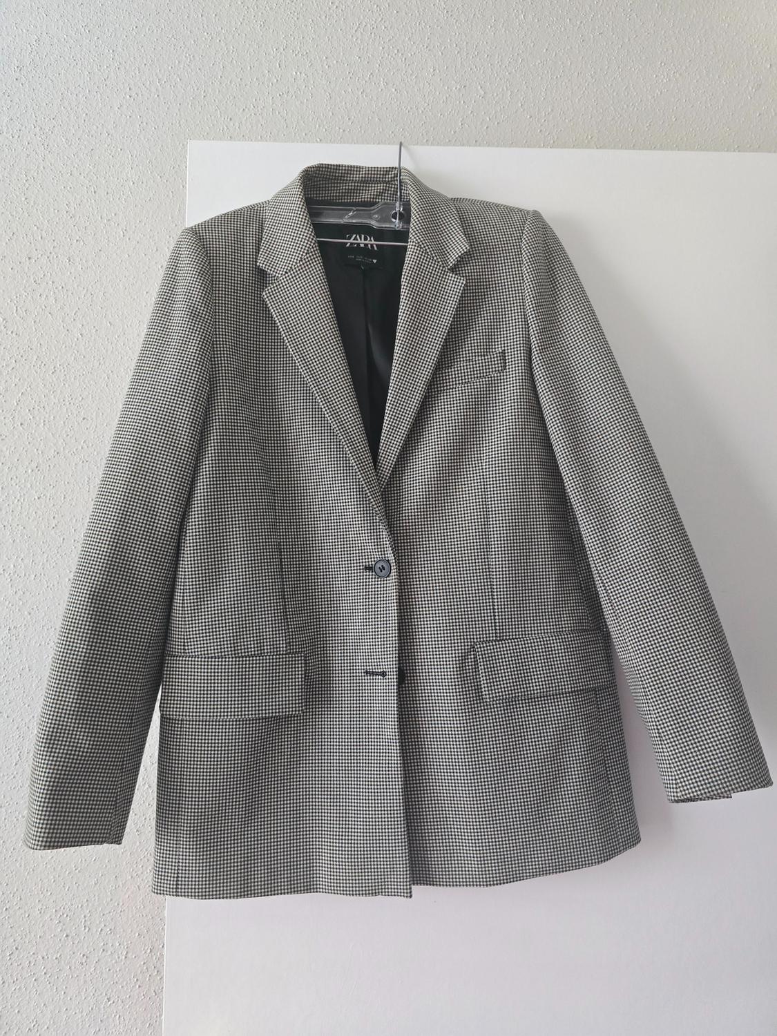 Front view of a gray jacket with a small check print, classic lapels, and front flap pockets.