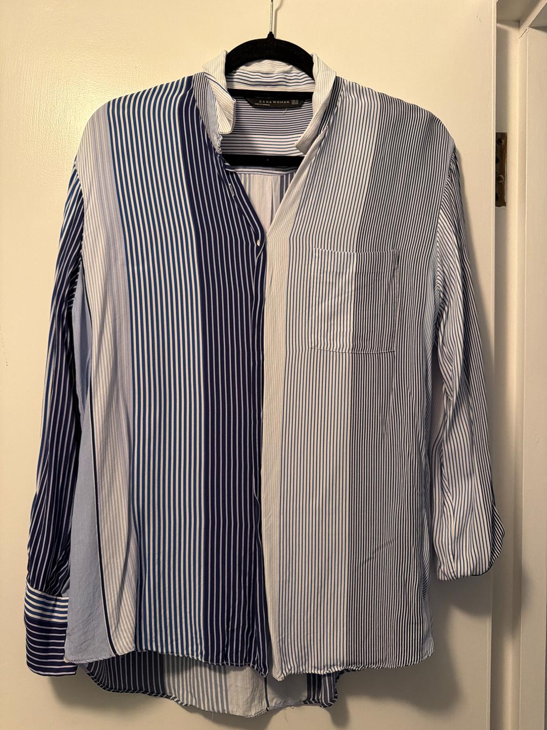 Blue and white striped shirt hanging on a black hanger. The label reads "Zara Woman". White background.