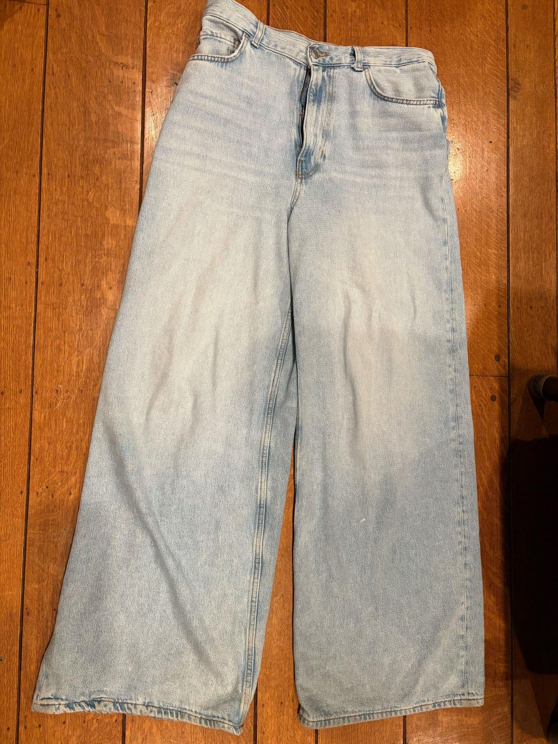 Light blue denim wide-leg jeans on a brown wooden floor.