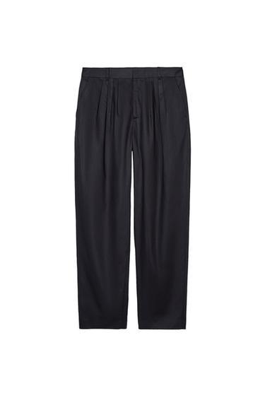 Front view of black pleated trousers with a belt-loop waistband.