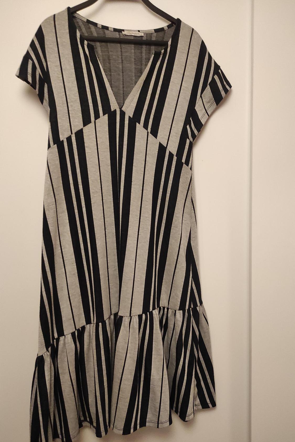 Front view of black and grey striped dress with V-neck and ruffles on the hem.
