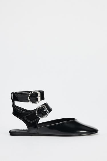 Boční pohled na černé boty se stříbrnými dvojitými přezkami a kulatou špičkou.