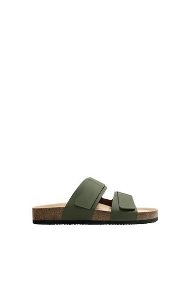 Side view of a green sandal with two wide straps adjustable with hook-and-loop fasteners and an anatomical footbed with a black sole.
