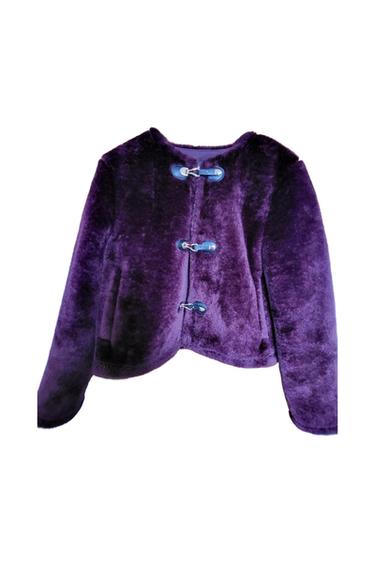 Purple faux-fur jacket featuring a round neckline and long sleeves. It has three blue toggle fastenings on the front against a white background.