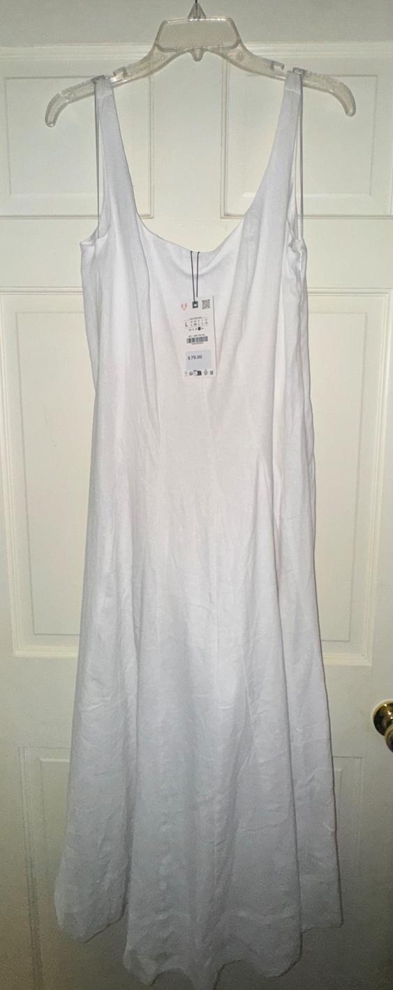 Long white dress hanging on a clear hanger in front of a white door. Visible tag with price of $79.90.