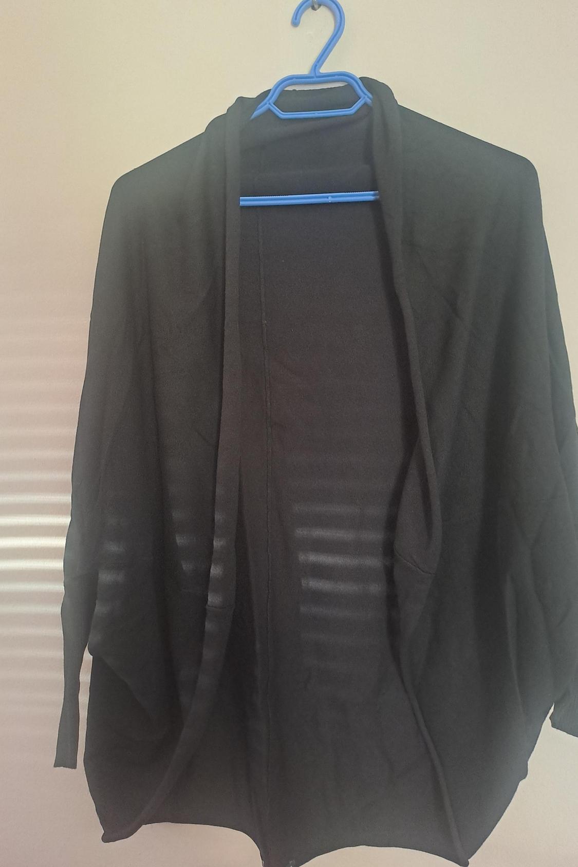 Front view of a black cardigan hanging on a blue hanger.