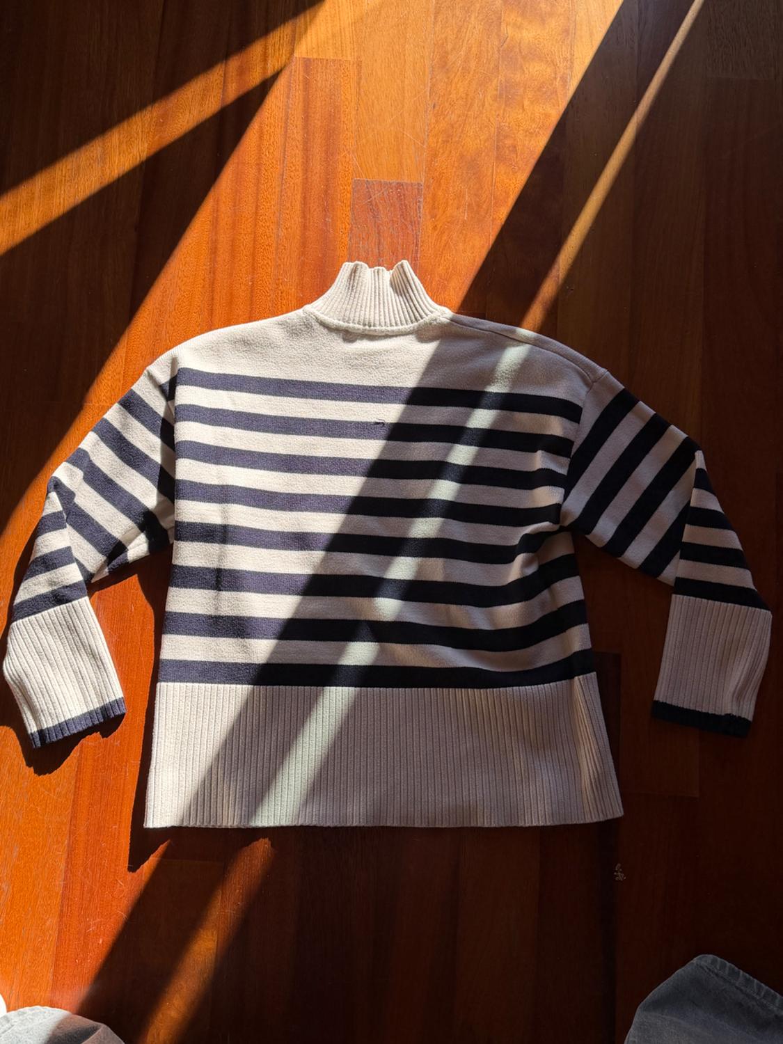 Navy and white horizontal striped jumper on a wooden floor, illuminated by diagonal sunbeams.