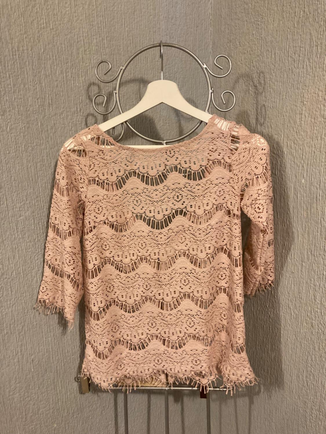 Front view of a pink lace blouse with three-quarter sleeves and a wave design.
