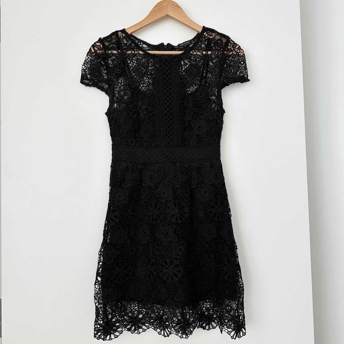 Front view of a black lace dress with short sleeves and floral detail.
