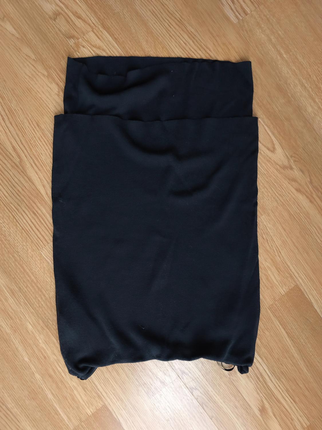 Black fabric folded on a light wooden floor.