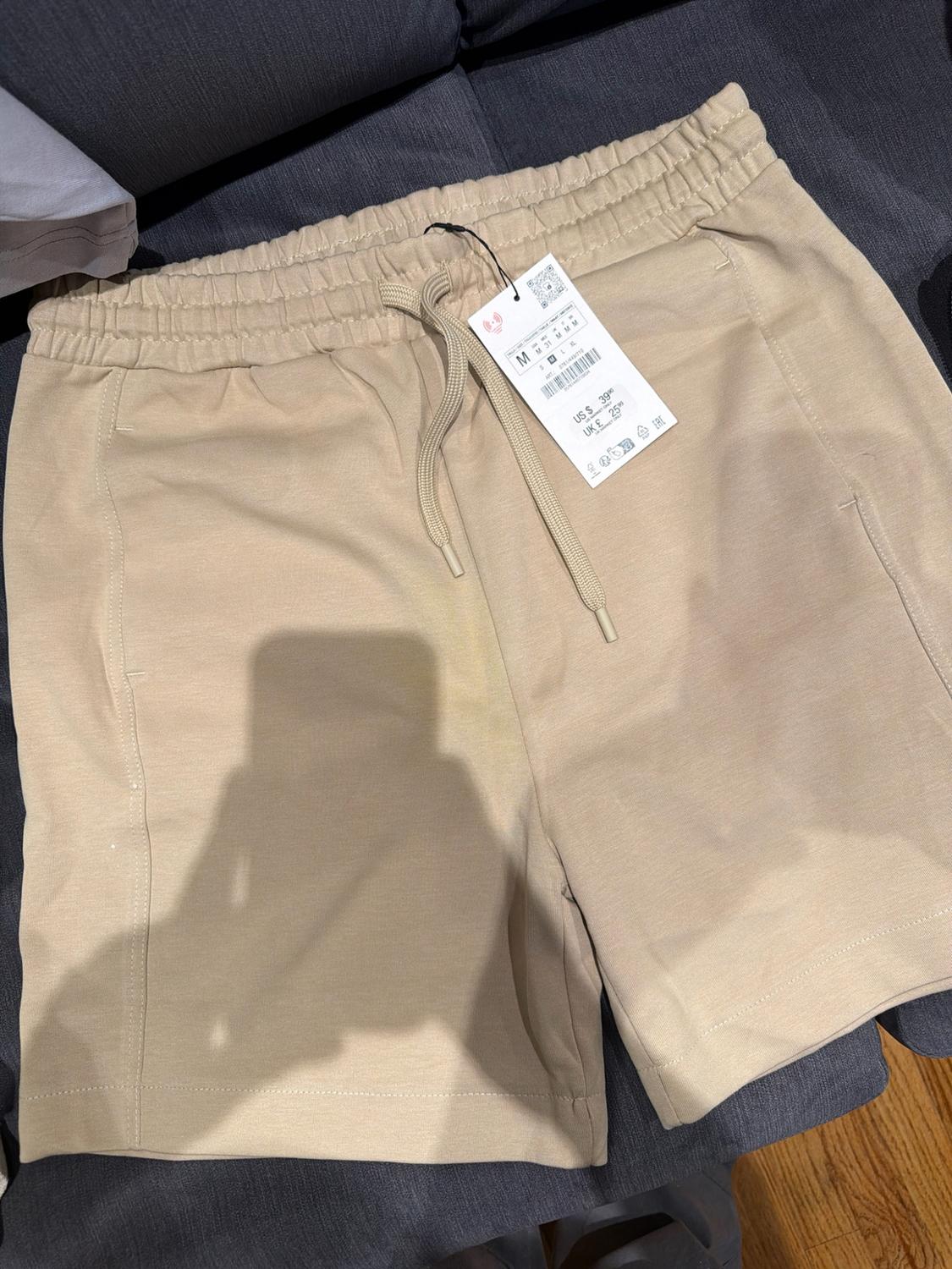 Beige shorts with an elastic waistband and drawstring. Visible price label with the texts US S 39.90 and UK E 25.99.