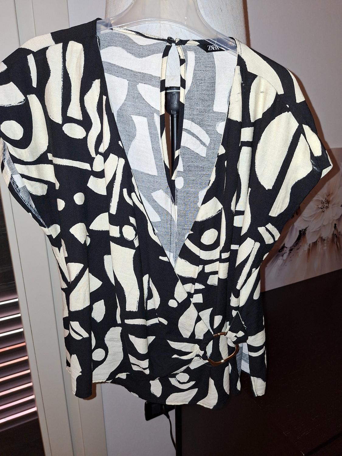 Black and white abstract print blouse, V-neck, and waist ring detail. Visible label at the neck.