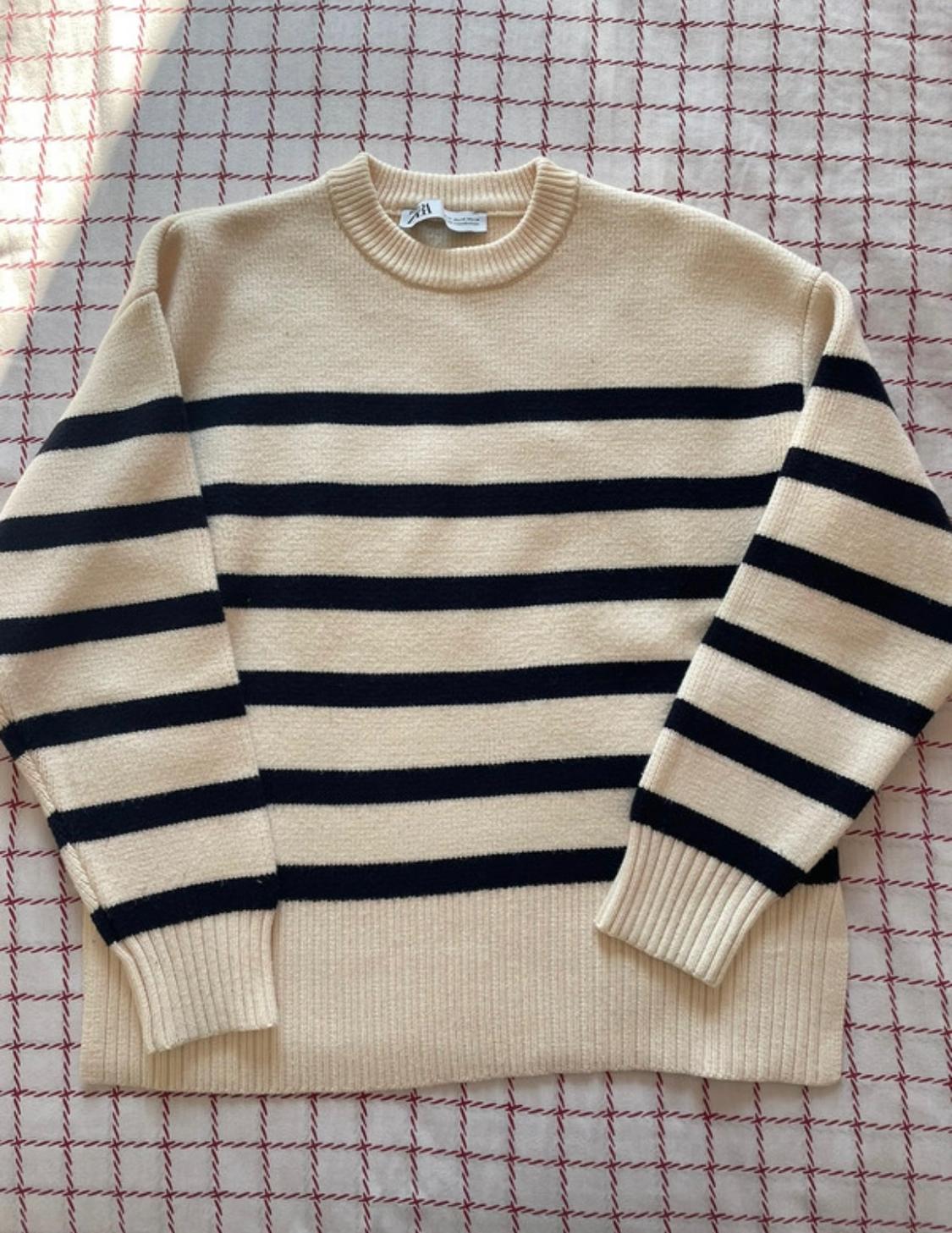 Beige jumper with horizontal black stripes on a background fabric with a red and white checked pattern.