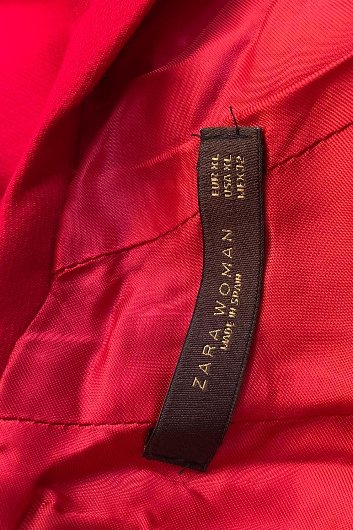 Detail of black label with text 'ZARA WOMAN MADE IN SPAIN EUR XL USA XL MEX 32' on red fabric.