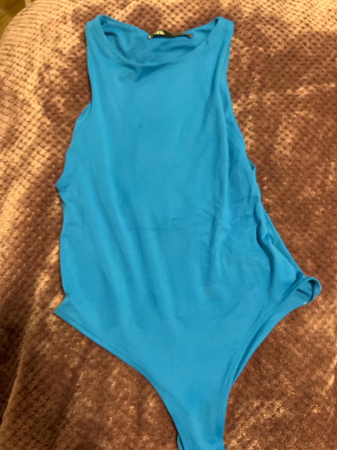 Sleeveless blue bodysuit on a textured brown blanket.