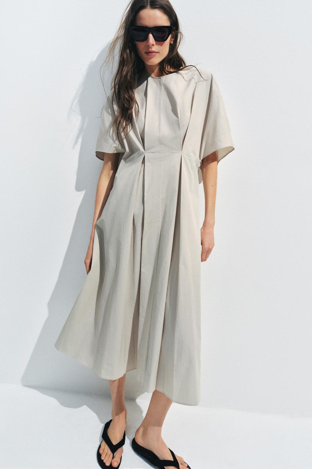 Conjunto de vestido gris claro midi con cuello redondo, mangas cortas y pliegues en la cintura. Bajo en línea evasé.