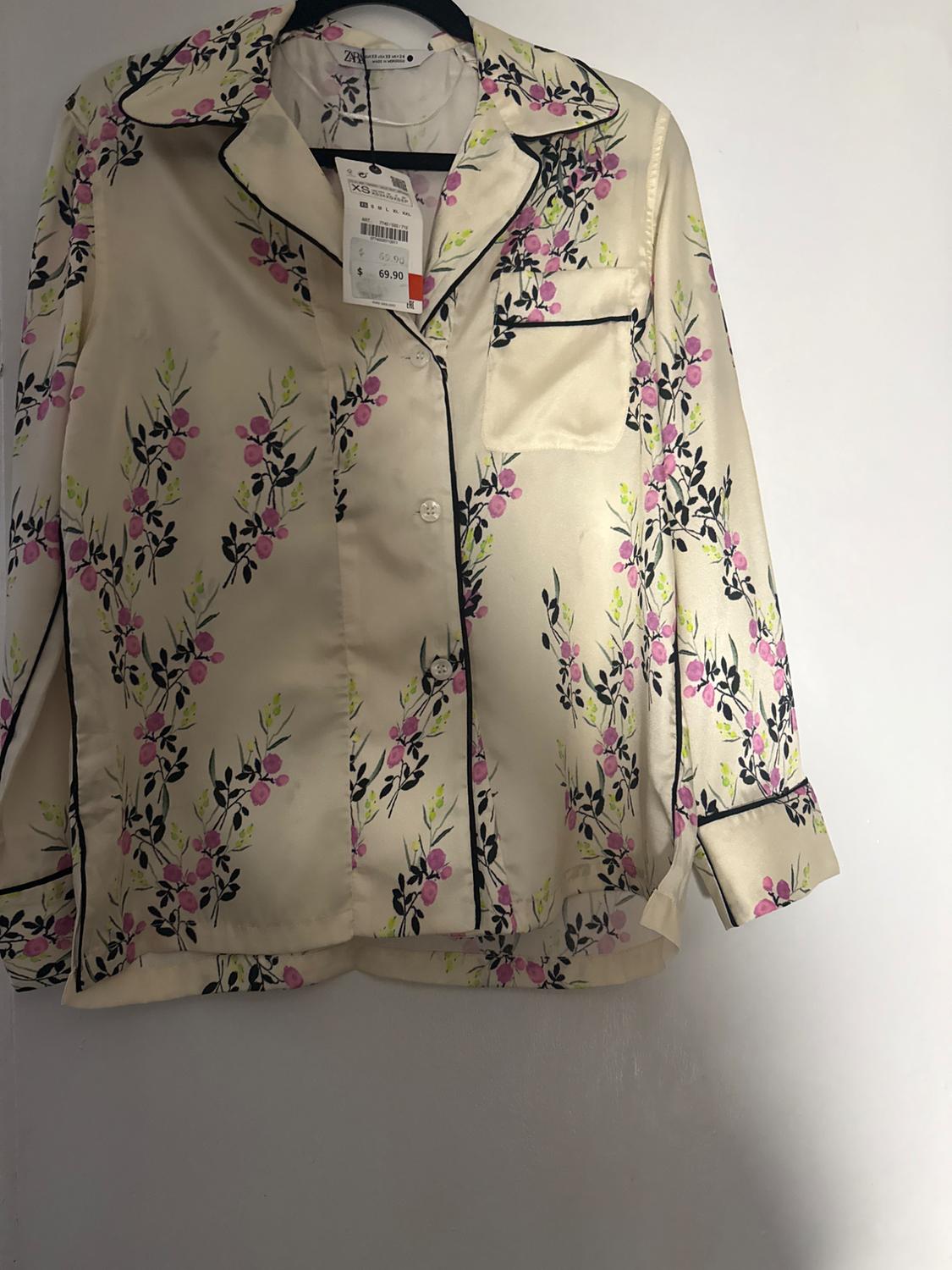 Satin shirt with a floral print in pink and black tones, hanging on a hanger. Visible tag with a price of $69.90.
