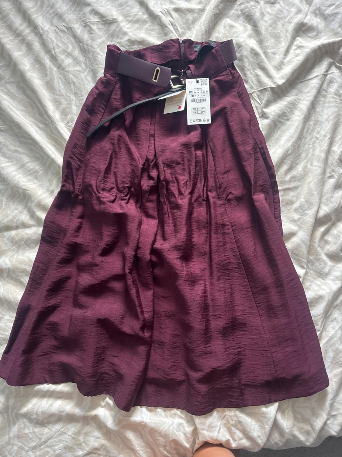 Burgundy crinkle-textured skirt with a matching belt and visible label, laid out flat on a white sheet.