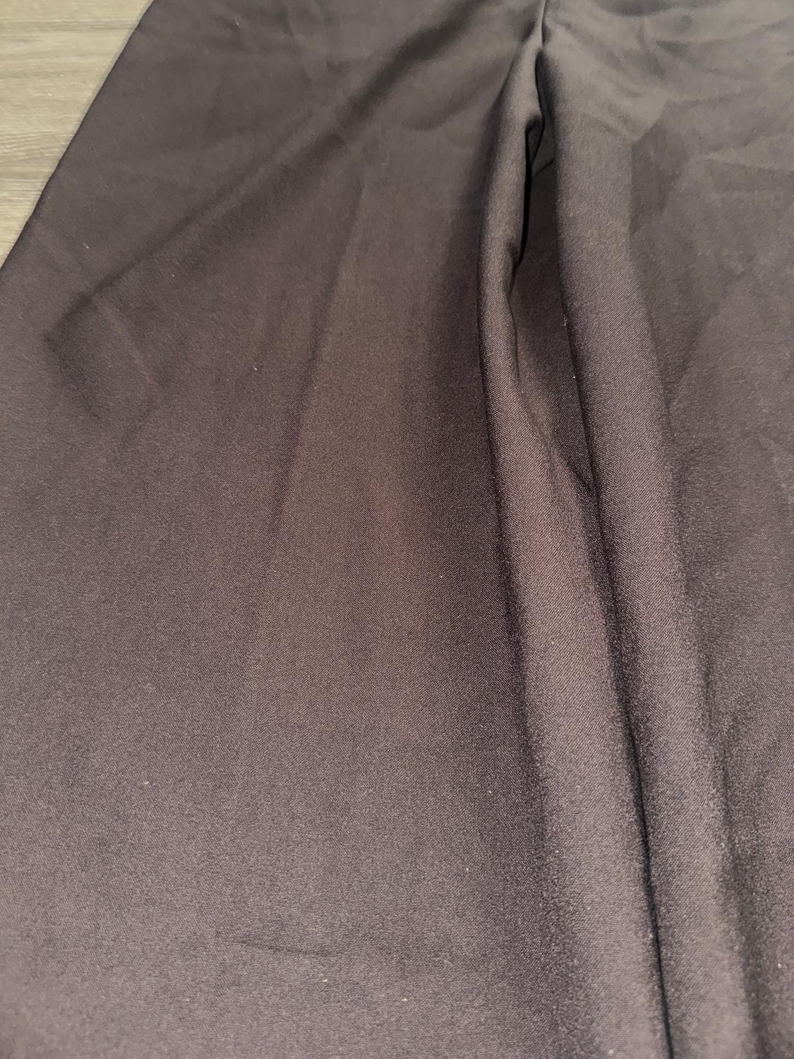 Smooth-textured black fabric with visible folds, spread across a light wooden surface.