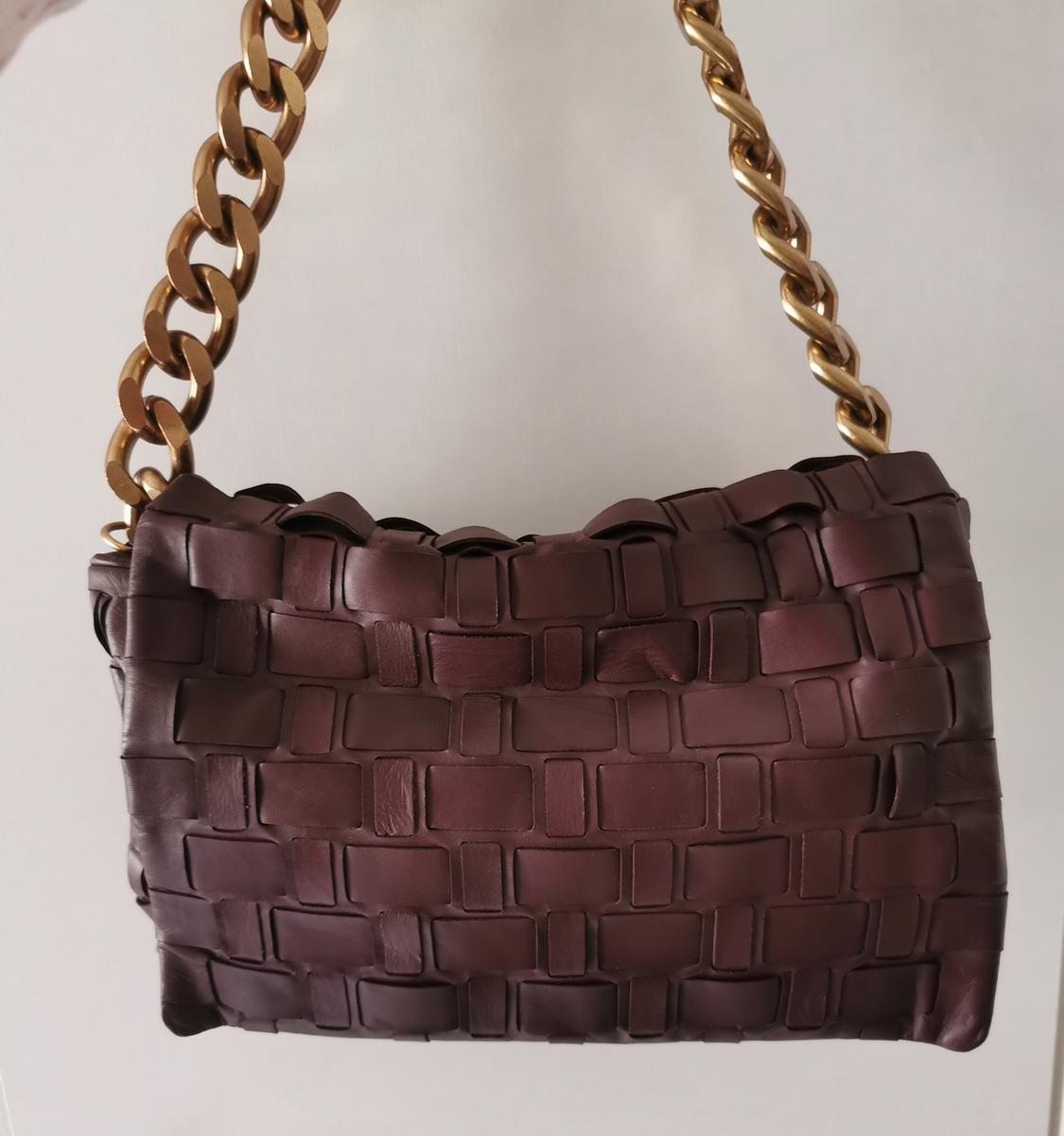 Brown woven handbag with a gold chain strap on a white background. Elegant and modern design.
