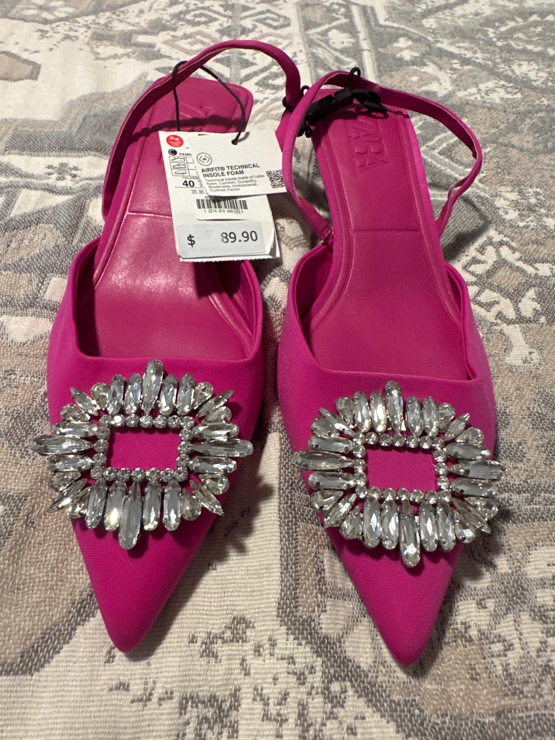 Fuchsia pointed-toe shoes with diamante buckles, price tag $89.90, on a geometric fabric background.