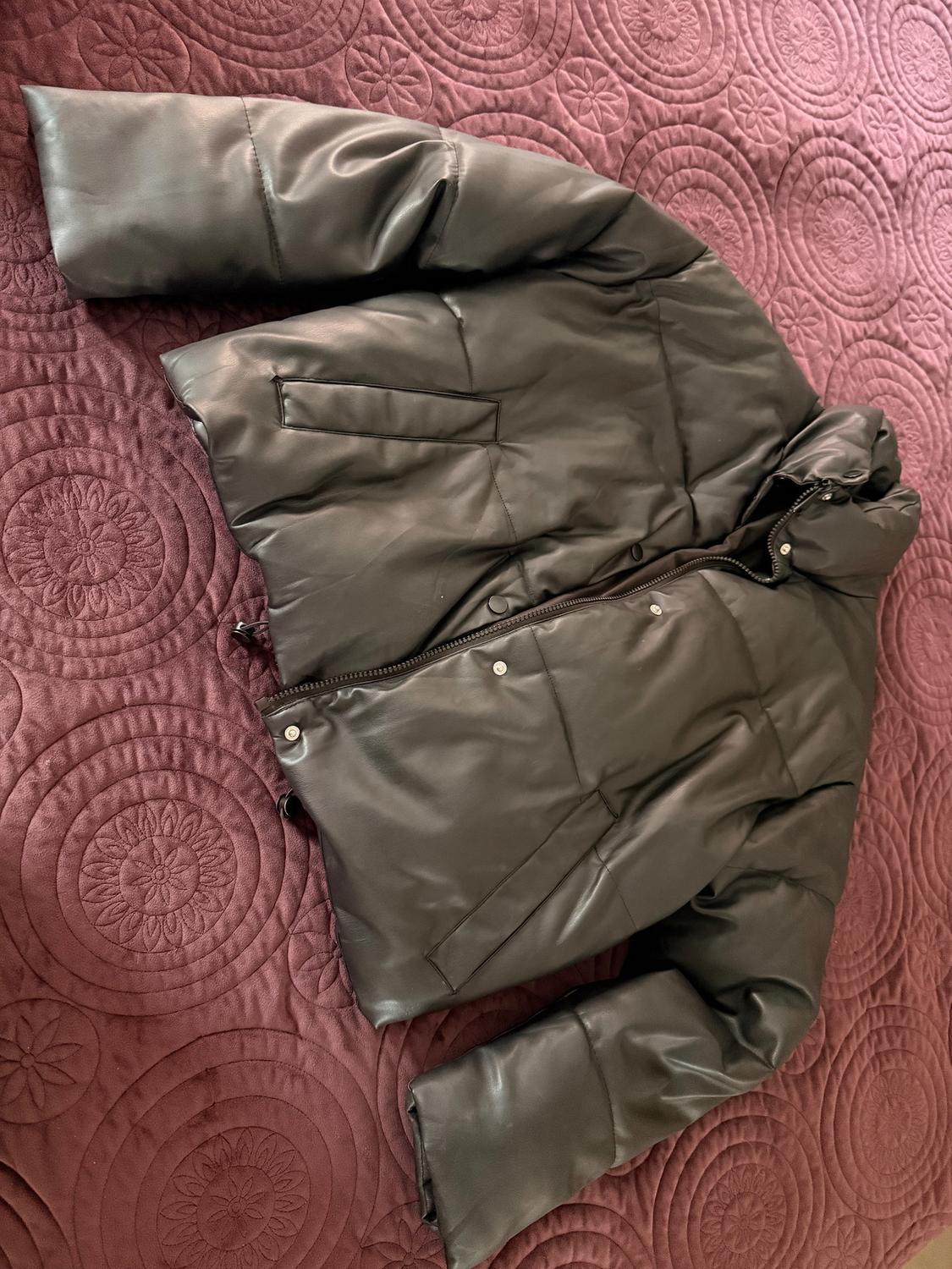 Black quilted jacket over a burgundy quilt with embossed circle and flower design.