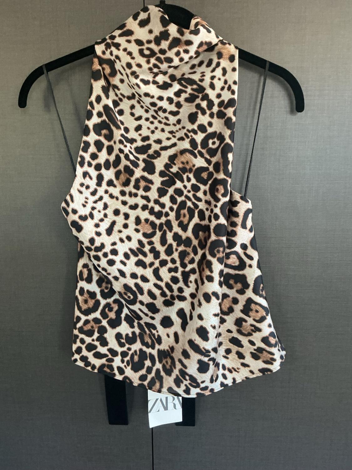 Leopard-print satin cami top hanging on a black hanger. Includes a tag with the text ZARA.