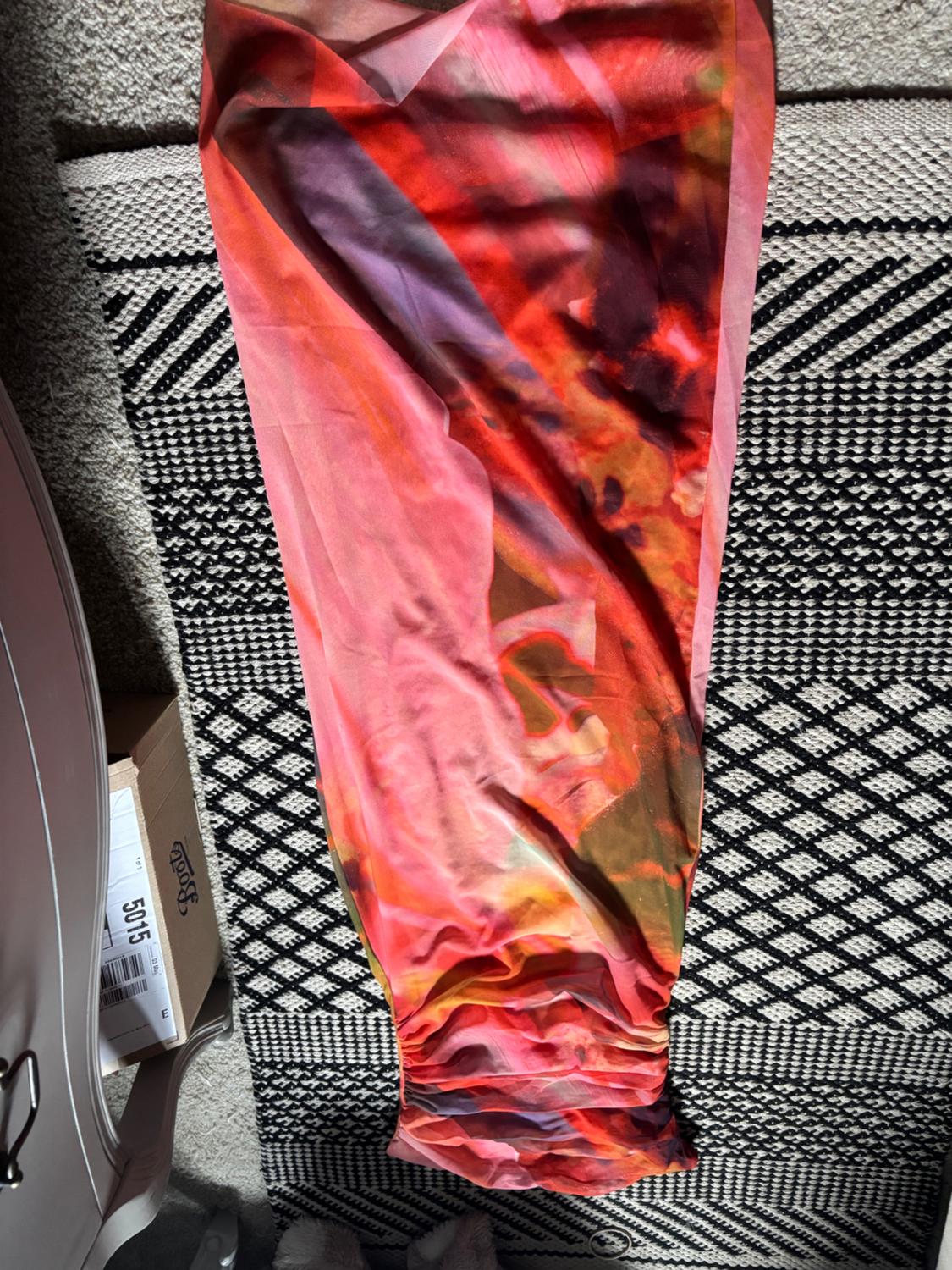 Multicoloured fabric flat lay with red and orange tones on a black and white rug.