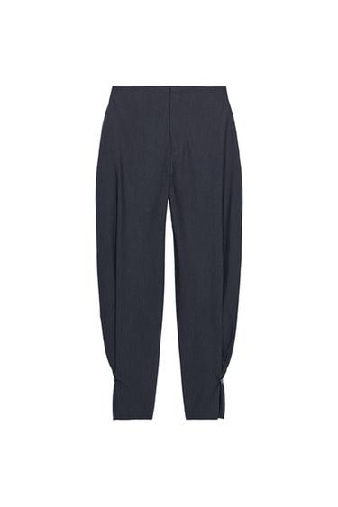 Front view of navy pinstripe trousers, high-waisted, concealed side pockets and adjustable hems with tab and button.
