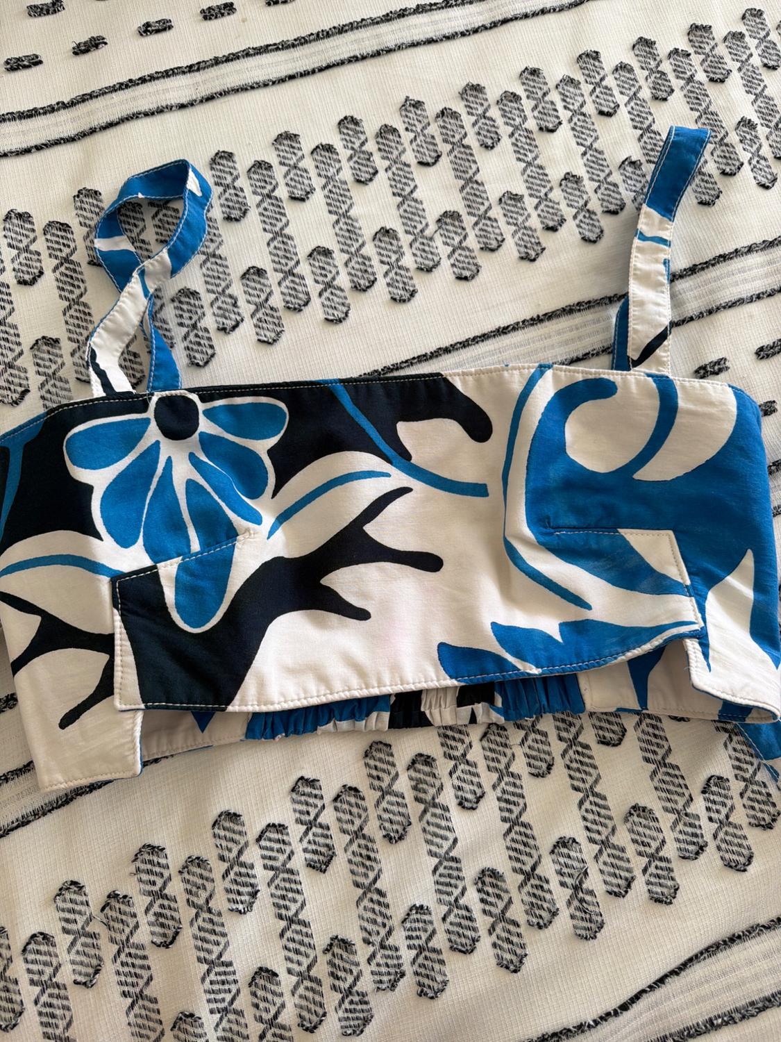 Blue and black floral print camisole crop top, on a white textured rug with dark geometric patterns.