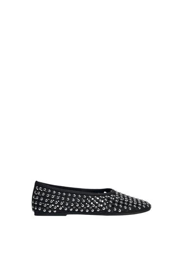 Black flat shoe with silver studs on a white background.
