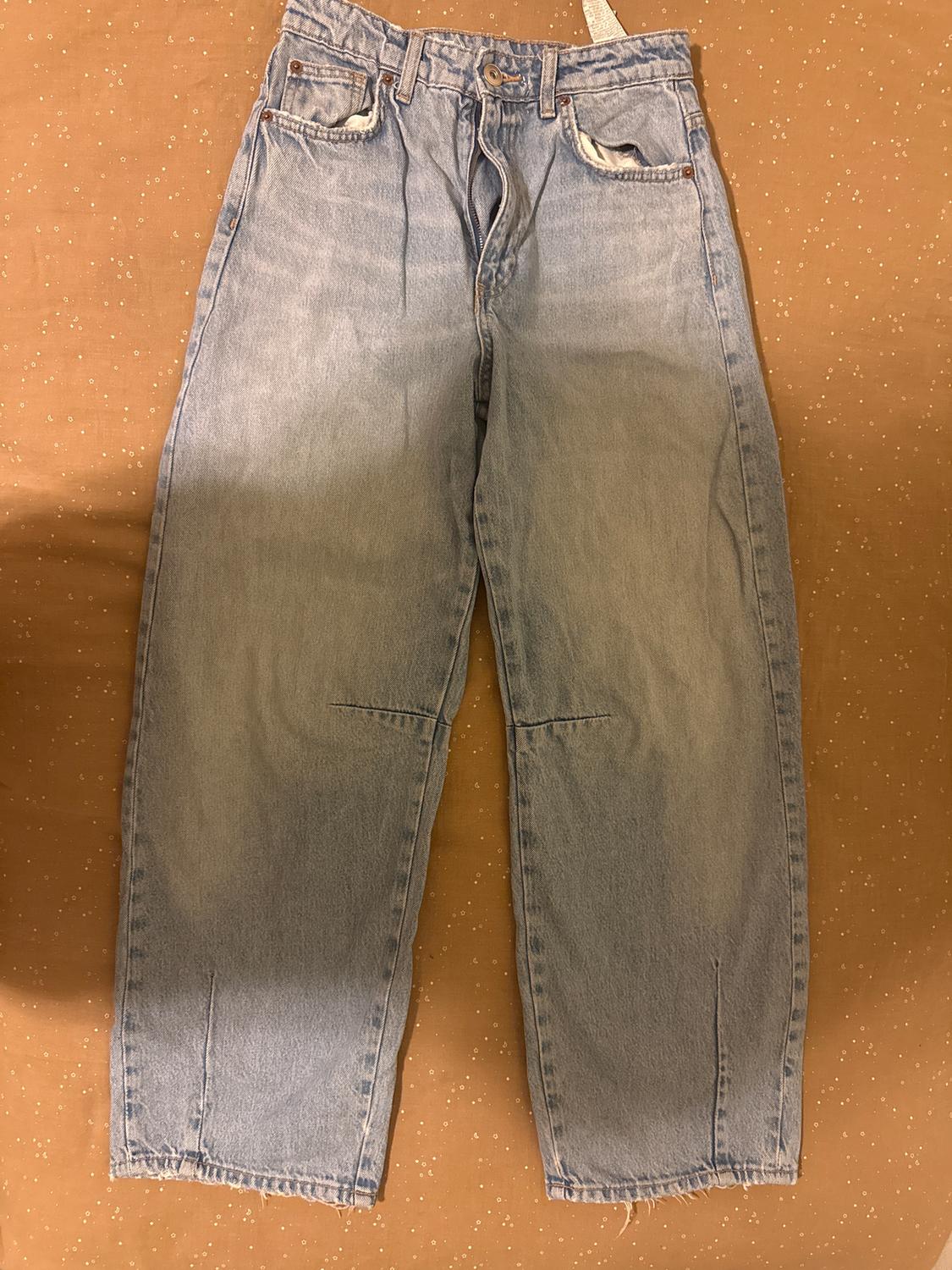 Blue straight-cut jeans on a brown surface with small white dots. Label visible at the top.
