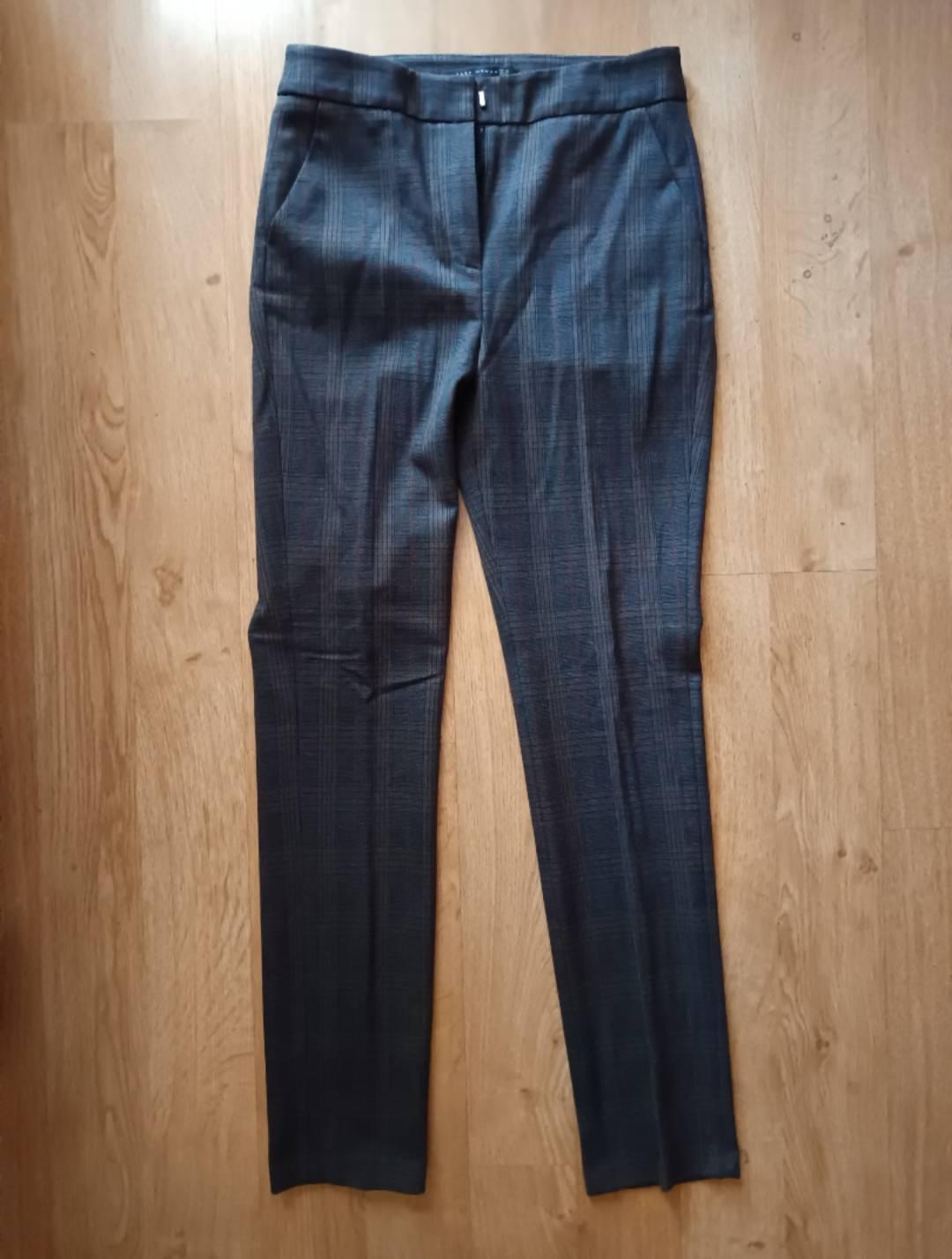Dark trousers with a checked pattern, laid out on a wooden floor.