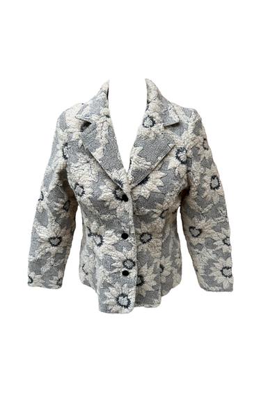 Grey jacket with a textured white floral print, a notched lapel collar and three black buttons down the front, against a white background.
