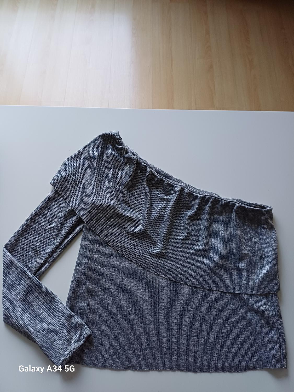 Front view of grey top with asymmetric neckline and long sleeves.