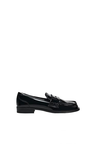 Black patent leather loafer photographed in profile against a white background.