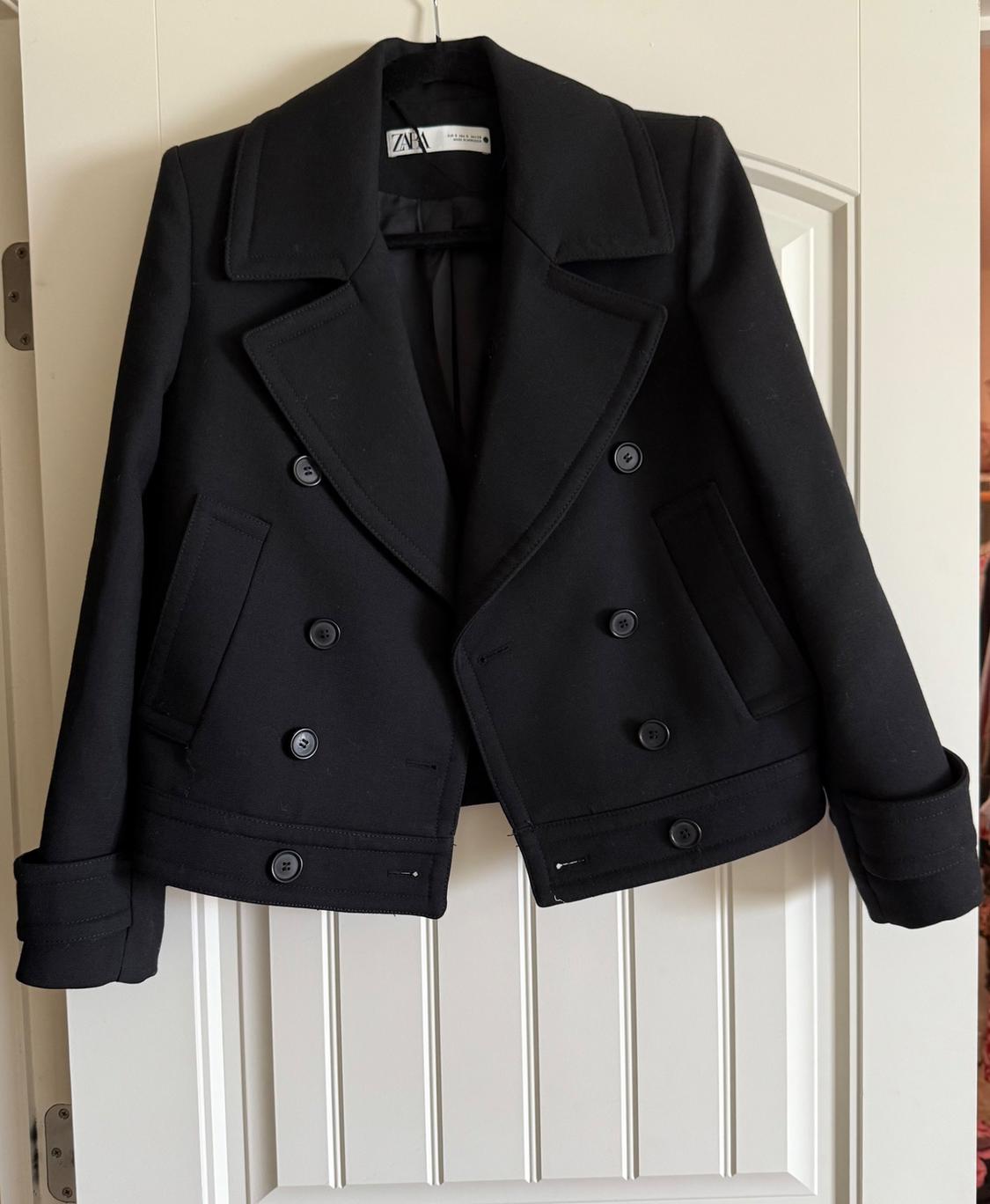 Front view of a double-breasted black jacket with side pockets