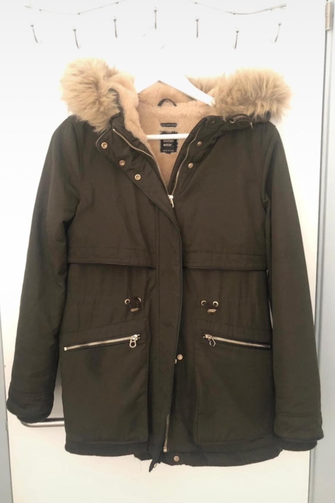 Front view of green coat with fur hood, zip and button fastening, zipped front pockets.