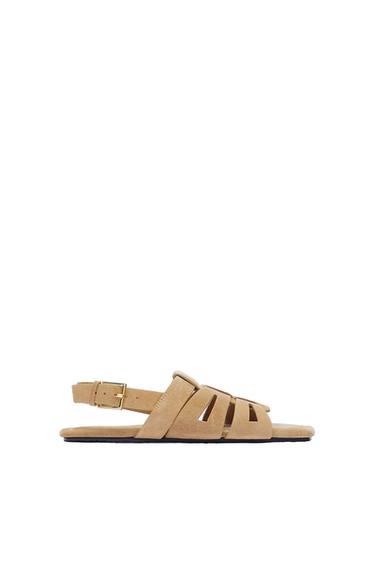 Side view of a beige sandal with a buckle fastening and interwoven straps.
