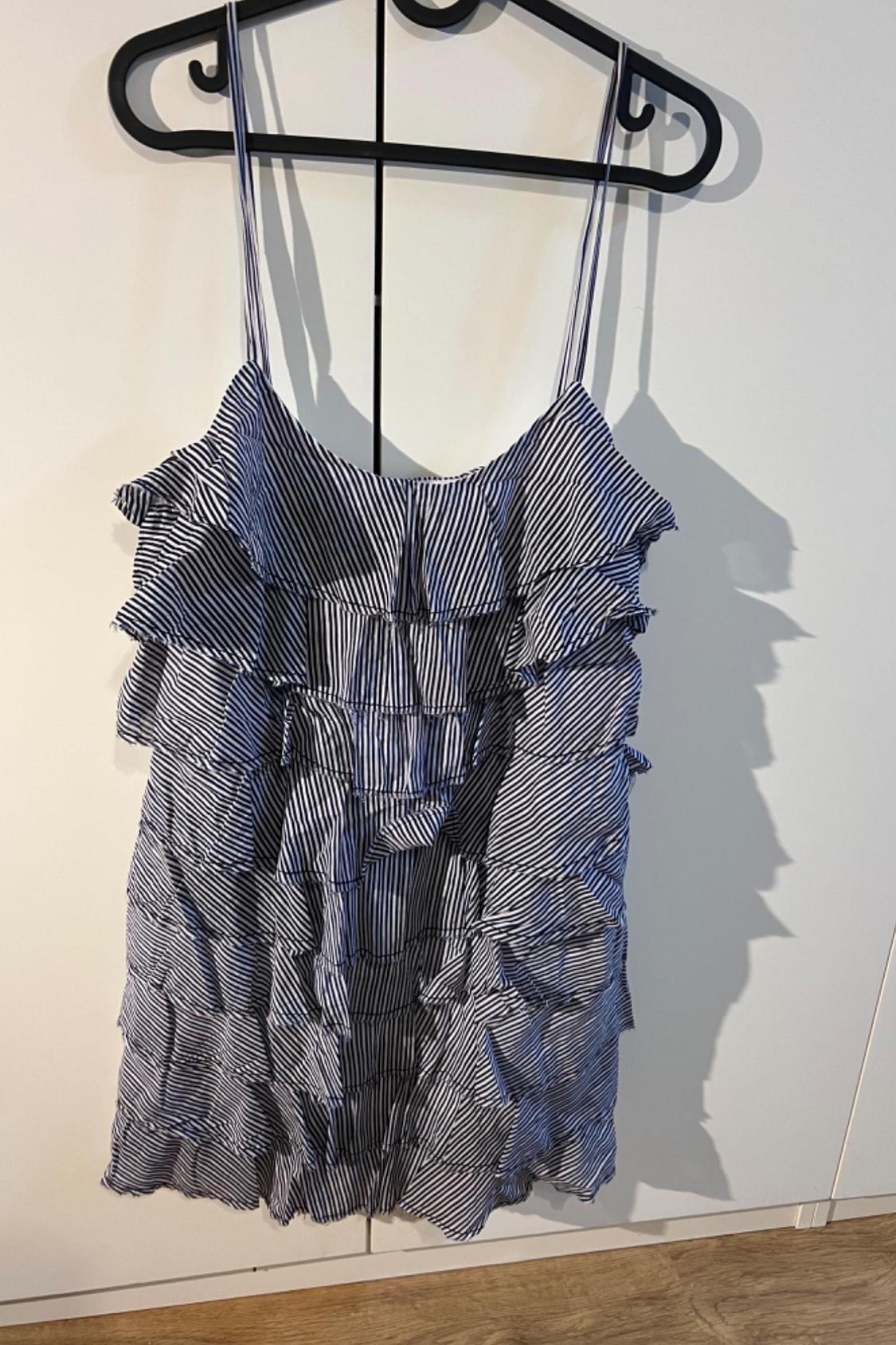 Front view of a black and white striped dress with straps and frills.